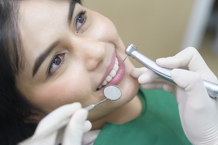 Dentista realizando check-up e limpeza dental em paciente